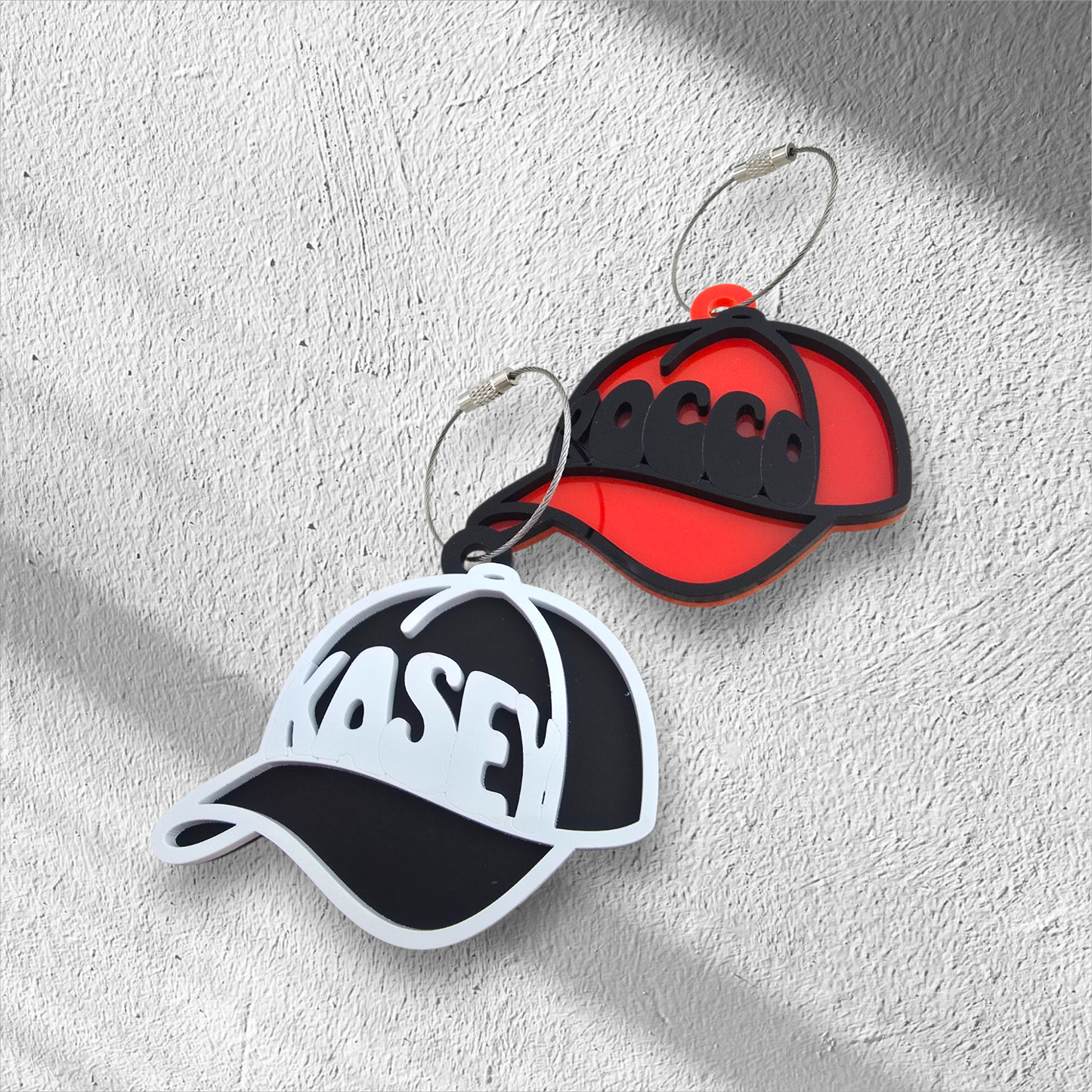 Two cap-shaped keychains or bag tags
