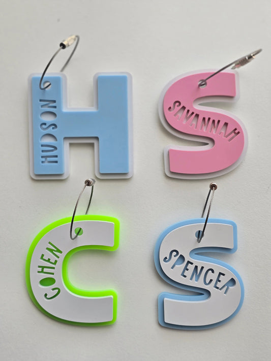 Four colorful letter-shaped name tags on a white background
